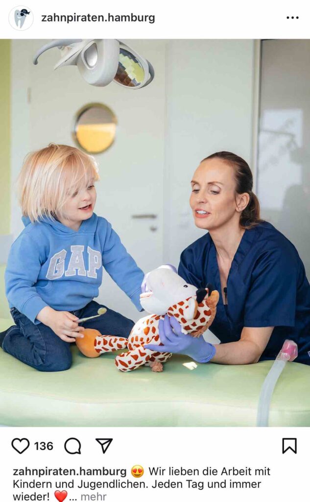 Zahnärztin zeigt einem kleinen Kind spielerisch die Zahnpflege mit einem Plüschtier in kindgerechter Praxis – authentischer Moment für Social Media Marketing einer Zahnarztpraxis.